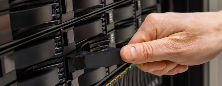 Cropped hand of male IT engineer replacing server drive from rack in SAN at datacenter